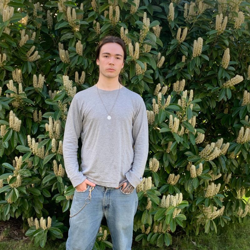 Aidan McMurray standing in front of a flowering laurel hedge